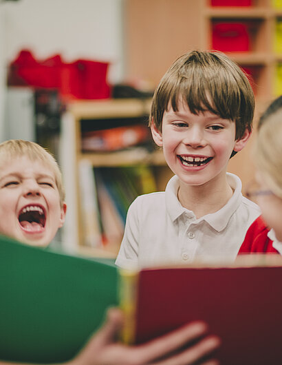 Kinder schauen lachend in ein Buch