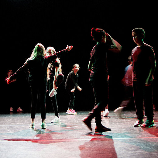 Tanzszene mit mehreren Personen auf einer Bühne.