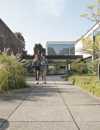 Foto vom Vorplatz eines Kunstvereins mit einem Paar, das dort entlanggeht.