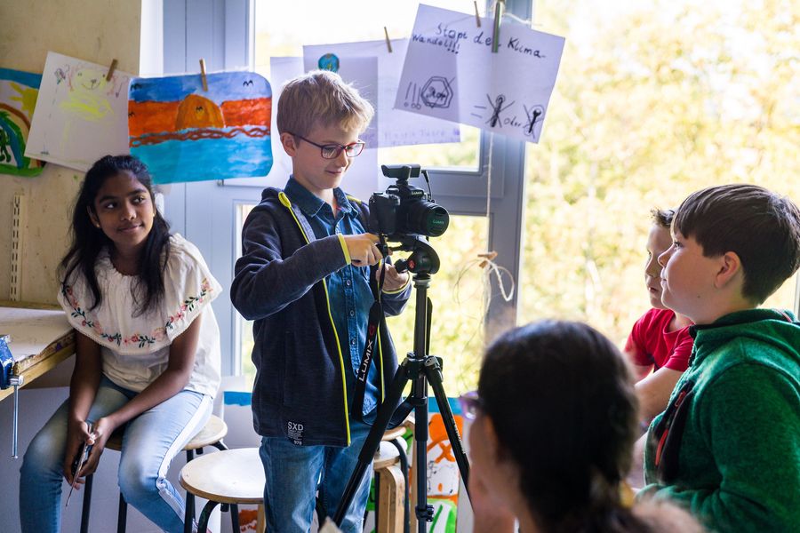 Kind mit Kamera auf Stativ