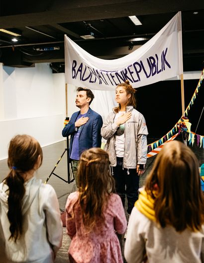 Im Vordergrund Kinder, dahinter ein Mann und eine Frau mit einem Banner.