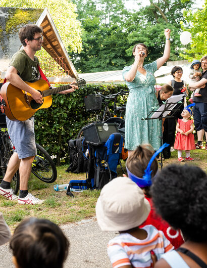 Familien mit kleinen Kindern lauschen der Musik von Gitarre und Gesang
