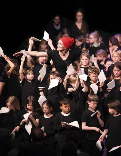 Kinder und eine Frau mit weißen Blättern.