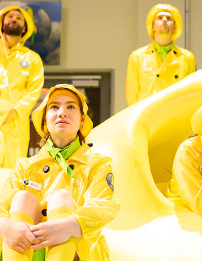 Theatergruppe: Mehrere Menschen in gelber Regenkleidung