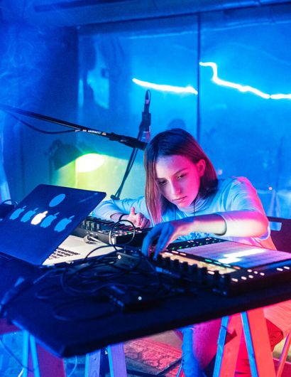 Zwei Jugendliche an einen DJ-Mischpult. Im Hintergrund Nebel und blaues Licht.