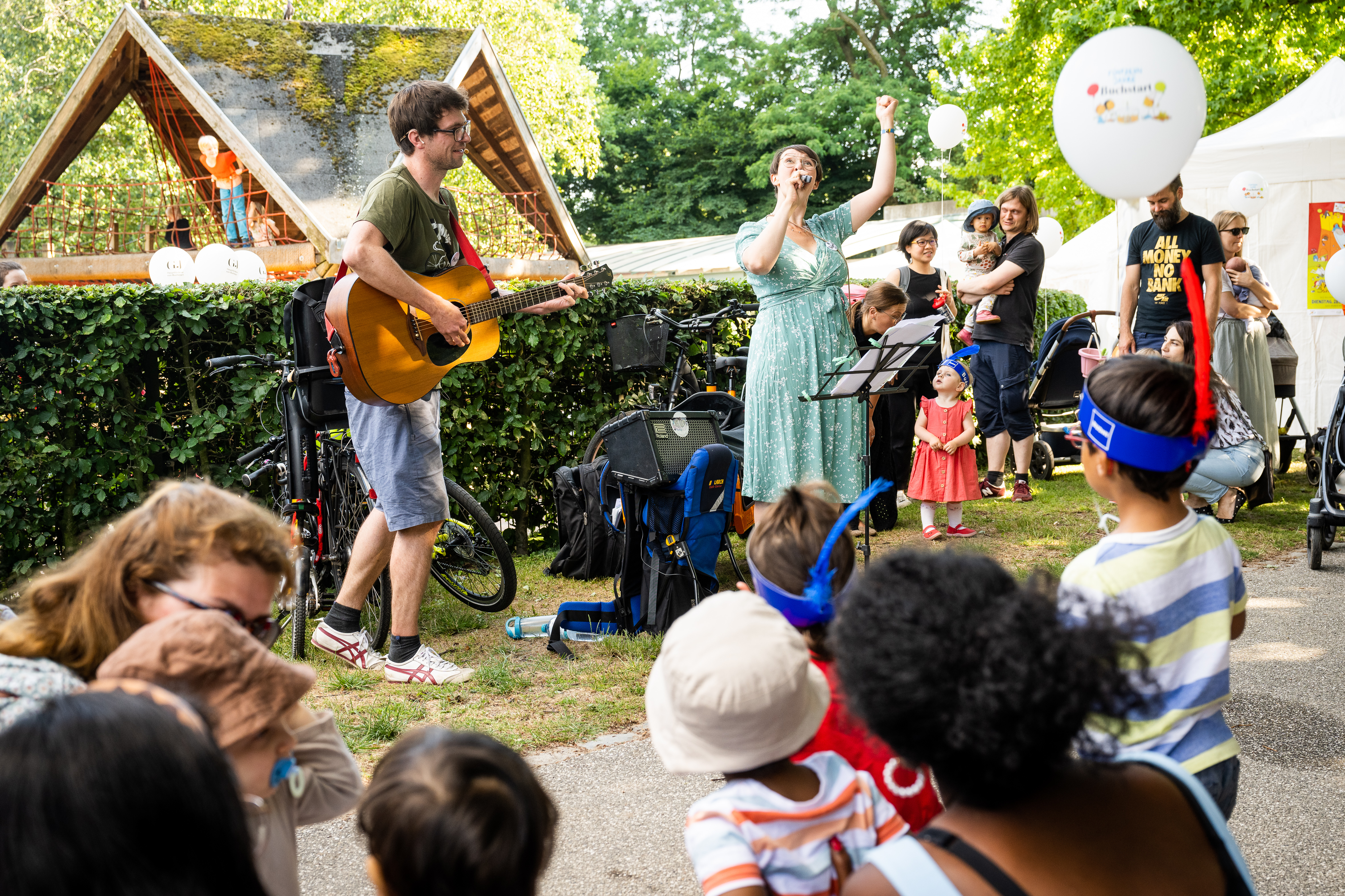 Familien mit kleinen Kindern lauschen der Musik von Gitarre und Gesang
