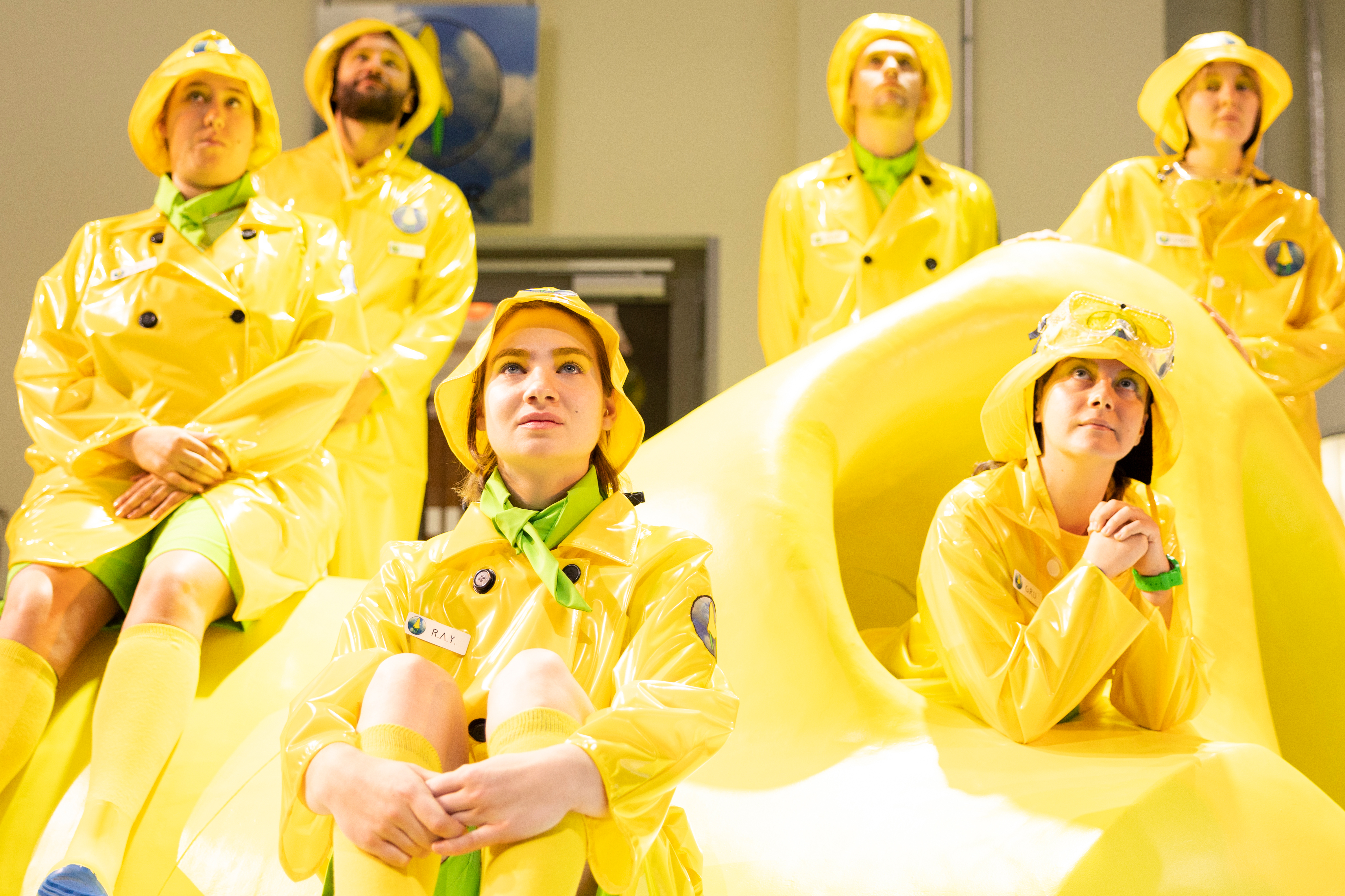 Theatergruppe: Mehrere Menschen in gelber Regenkleidung